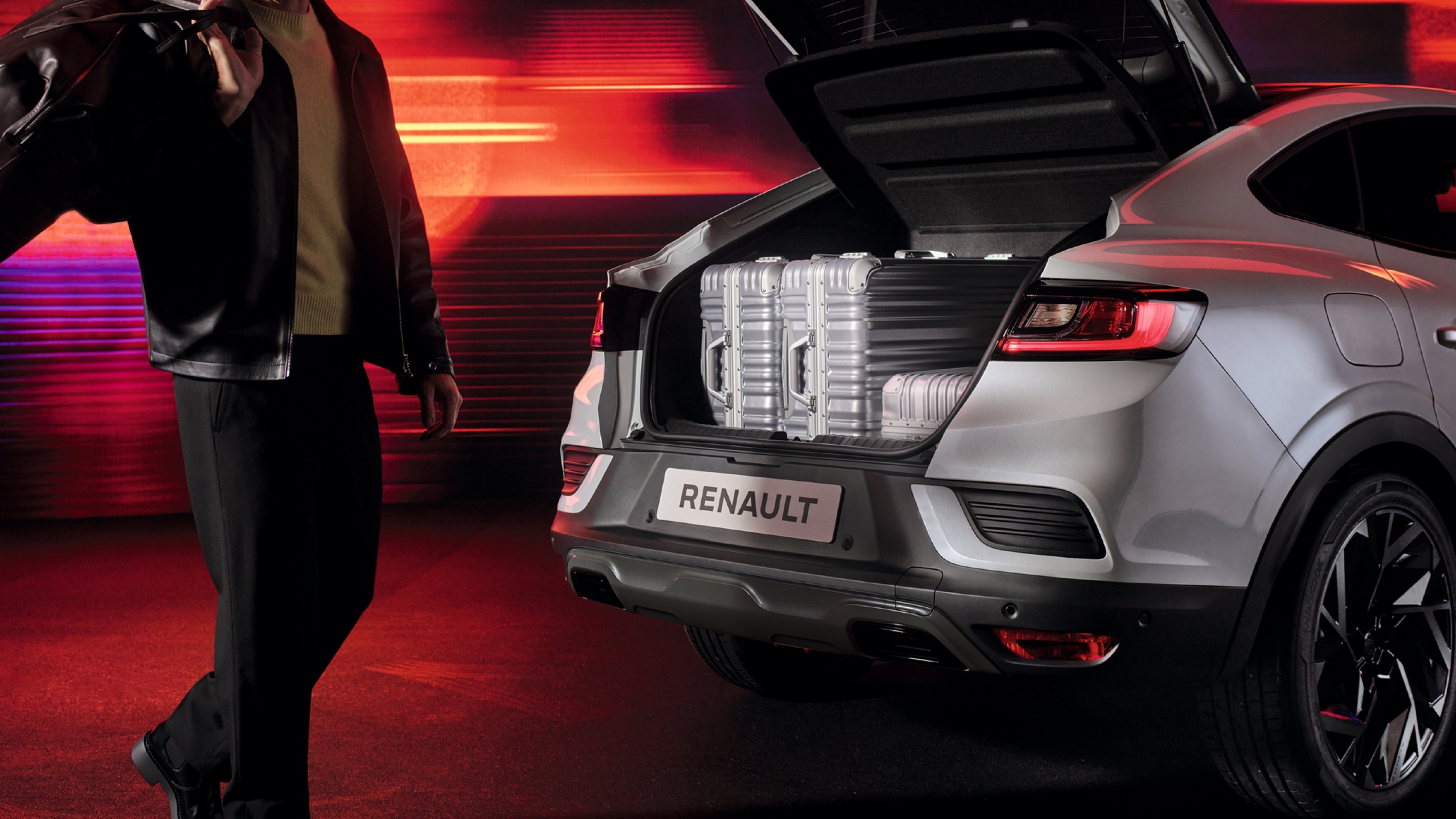 Vista trasera de Renault Arkana con el baúl abierto y maletas dentro de él.